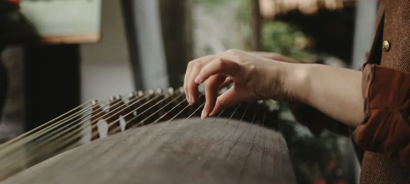 Close-up of a player's hand plucking the strings of a guzheng
