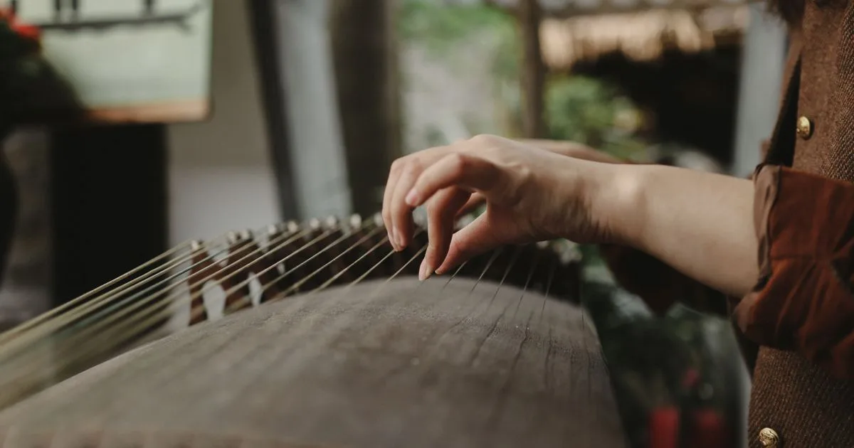 Close-up of a player's hand plucking the strings of a guzheng