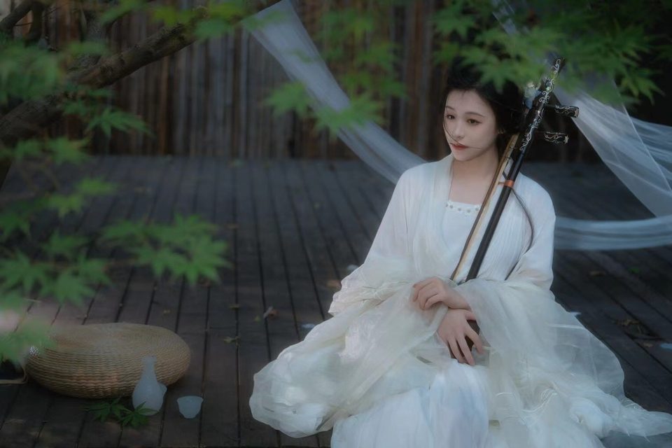 Lu Shujie seated with her erhu beneath maple leaves